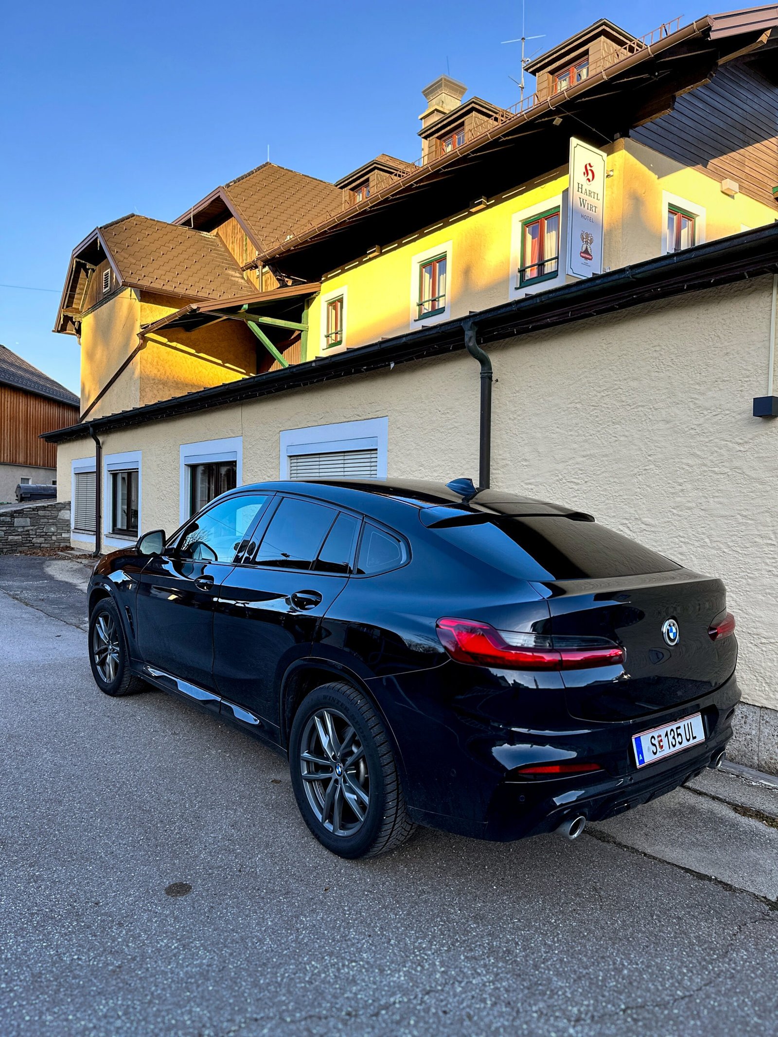 Bmw X4 in schwarz, mit schwarze getönte scheiben, steht vor einem Hotel