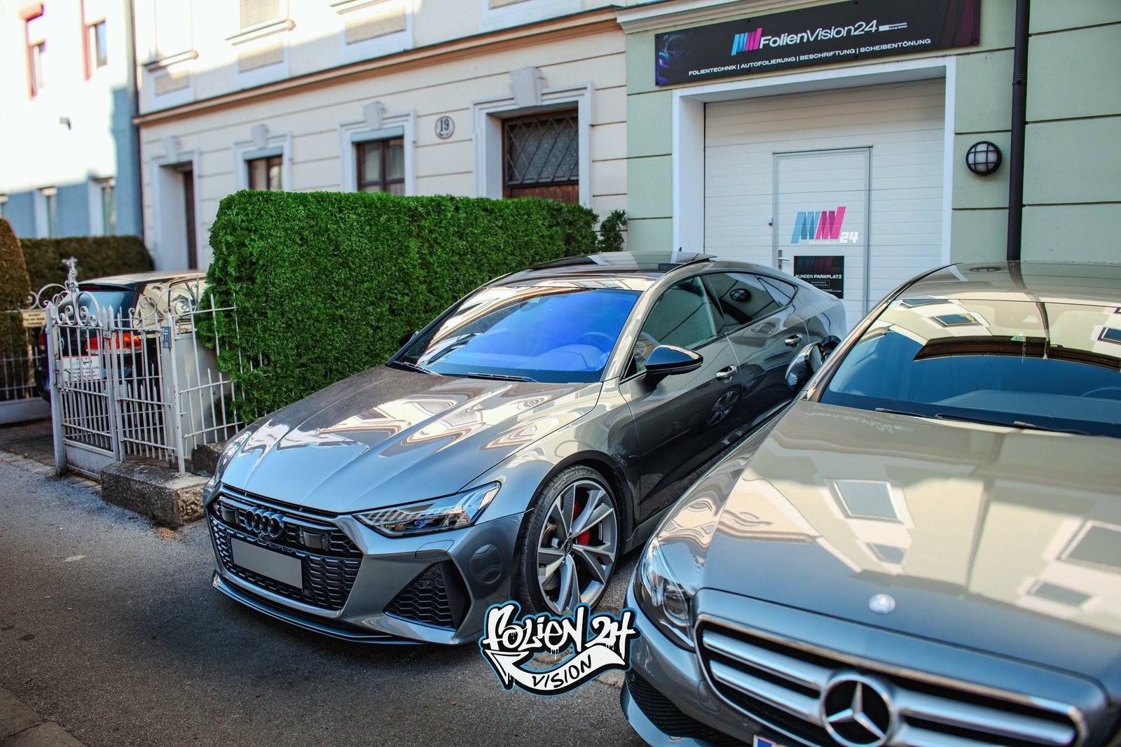 Getönte Scheiben an einem grauen Audi RS7 vor dem FolienVision 24 Studio für Scheibentönung in Salzburg