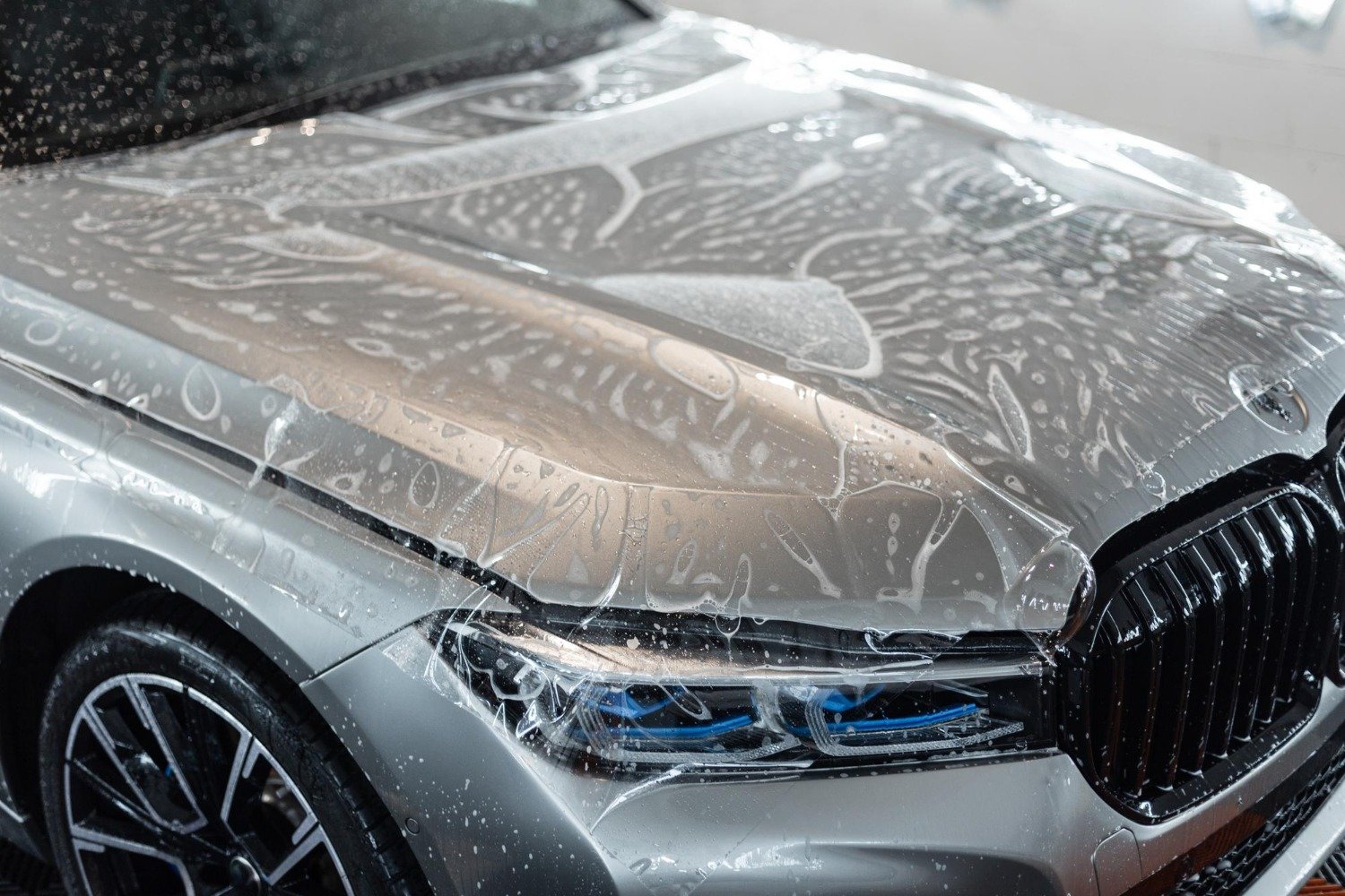Montage einer transparenten PPF-Lackschutzfolie auf der Motorhaube eines Fahrzeugs zum Schutz vor Steinschlägen und Kratzern.