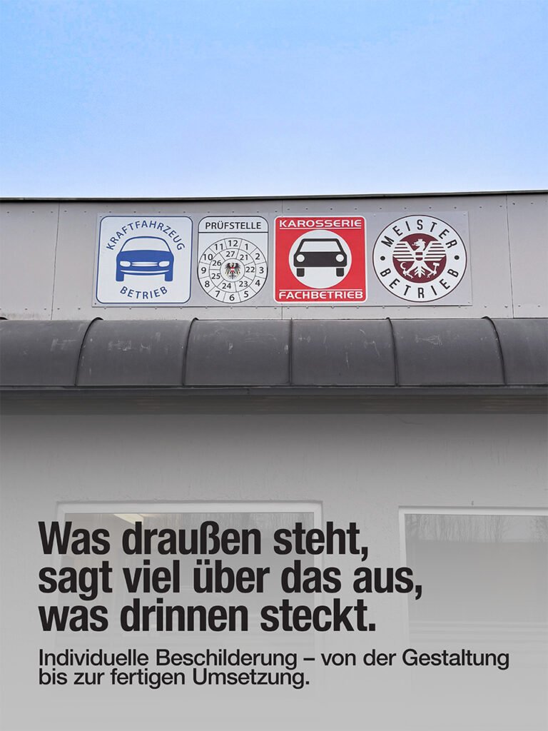 Das Foto zeigt vier Schilder an einer Werkstattfassade.